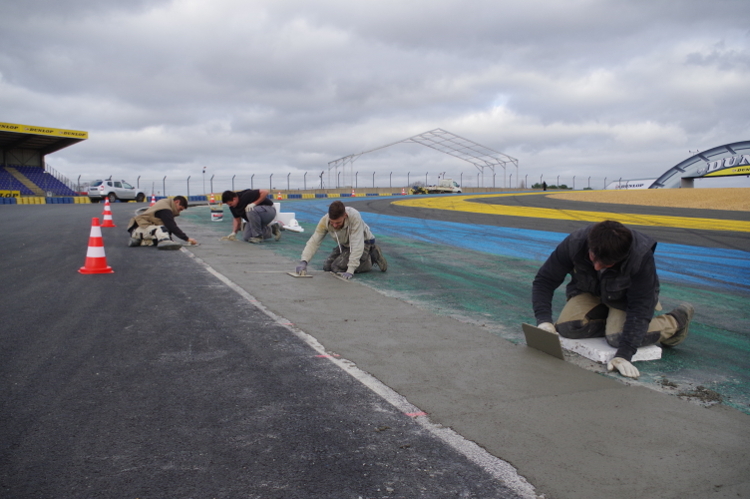 Arbeiter formen die Randsteine vor dem Dunlop-Bogen auf der Rennstrecke in Le Mans