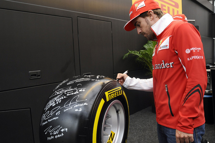 Fernando Alonso signiert den Rennreifen