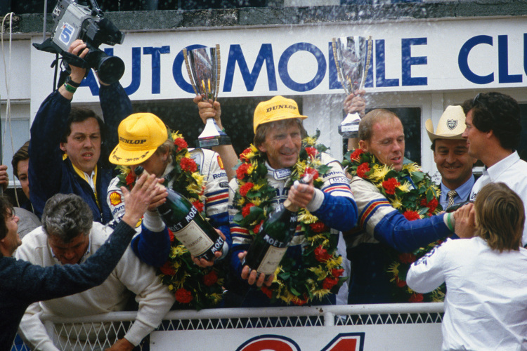 Derek Bell (Mitte mit Mütze) bei seinem Le-Mans-Sieg 1986 an der Seite von Hans-Joachim Stuck (li.) und Al Holbert