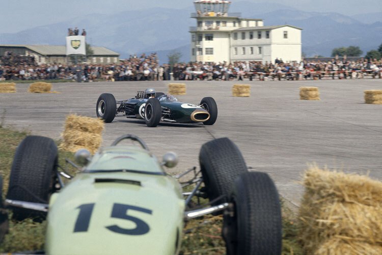 Jack Brabham fährt 1964 in Zeltweg am  kaputten Auto von Trevor Taylor vorbei