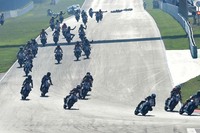 Im Hintergrund sind die Personen und zerstörte Motorräder auf der Startgeraden zu erkennen