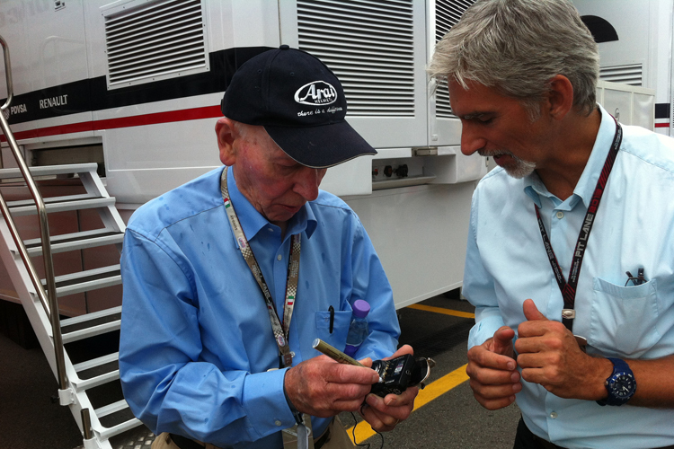 Formel-1-Weltmeister unter sich: John Surtees und Damon Hill signieren eine Fotokamera