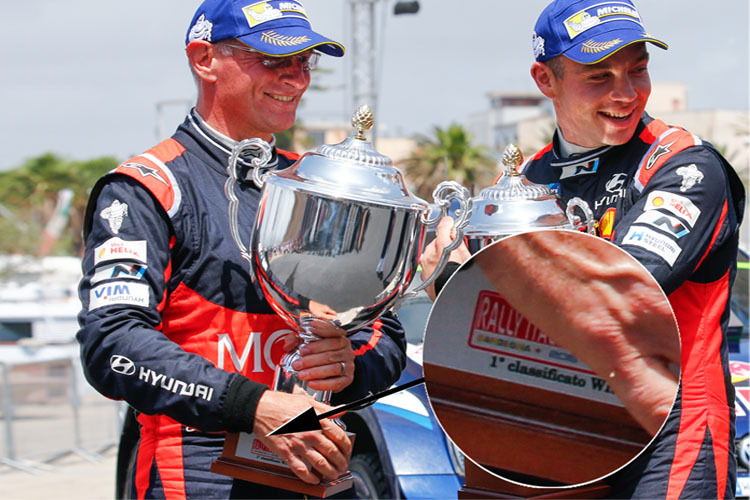 Podium der Rallye Italien. Hayden Paddon (rechts) und Beifahrer John Kennard wissen’s schon – die erhaltenen Pokale gehören eigentlich den Siegern (siehe Ausschnitt)