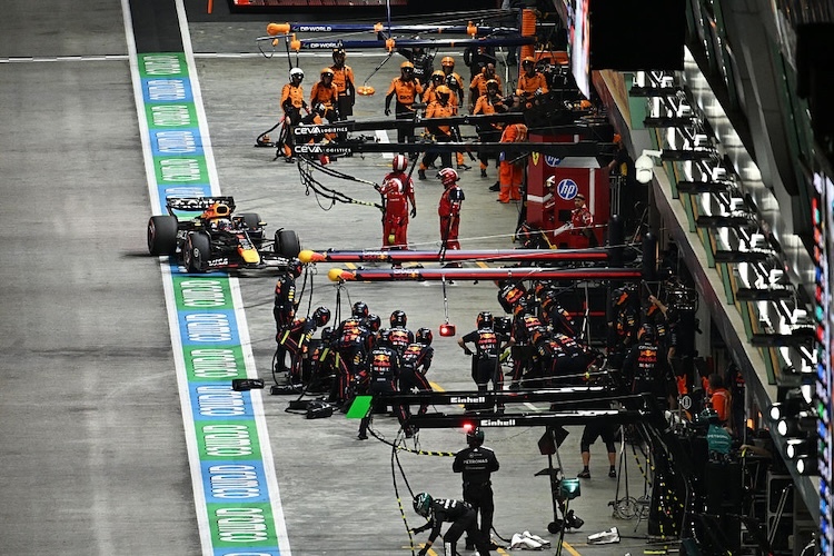 Max Verstappen auf dem Weg zum Boxenstopp in Singapur. Dahinter: die McLaren-Crew