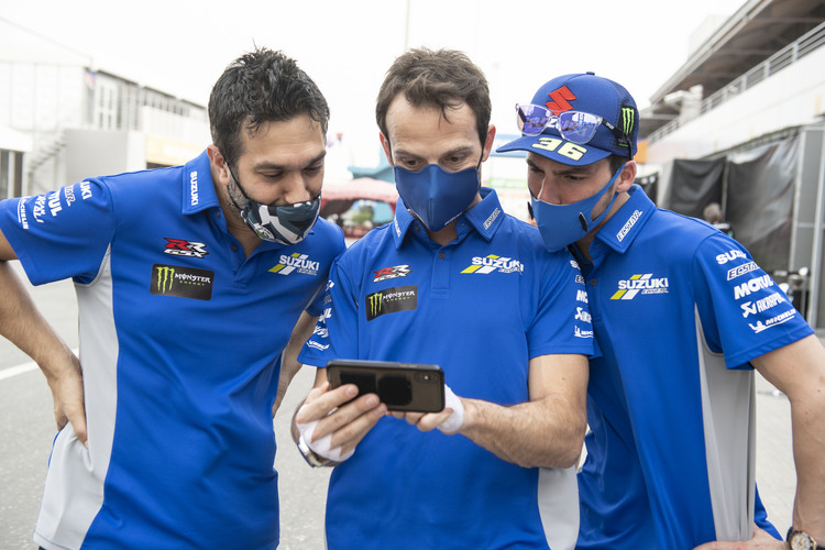 Joan Mir (rechts) steckt mit seinem Crew-Chief Francesco Carchedi (li.) und Testfahrer Sylvain Guintoli die Köpfe zusammen