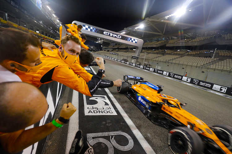 Carlos Sainz flitzt durchs Ziel, die McLaren-Mechaniker jubeln